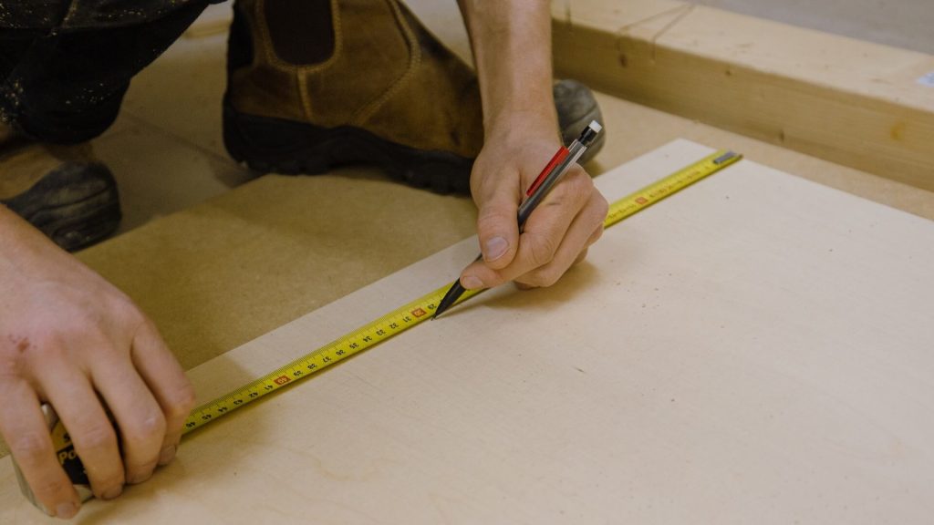 A person measuring a piece of wood